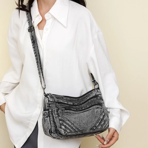 Detail of vintage denim crossbody bag with multiple zippers and adjustable strap