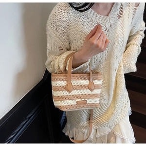 Close-up of woven bucket bag with cream and brown stripes and leather handle
