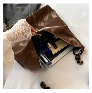 Detail view of large dark brown leather tote interior with wooden beads and daily essentials
