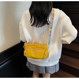 Detail of yellow nylon crossbody bag with multi-zipper pockets and wide letter strap