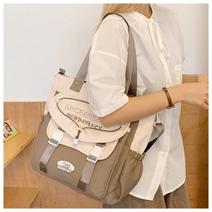 Detail view of large canvas crossbody bag with earth-tone patchwork and buckle closures