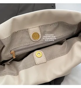 Detail view of cream pleated bucket bag showing magnetic snap and internal zip pocket