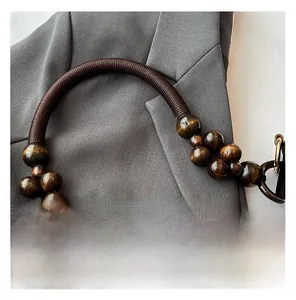 Detailed shot of dark brown woven rope strap with polished wooden beads and metal buckle