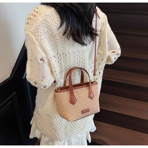 Detail view of woven straw tote bag with brown leather handles and adjustable shoulder strap
