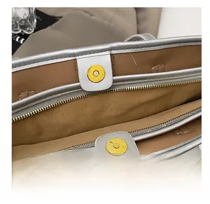 Détail du sac cabas argenté montrant la fermeture magnétique et le zip métallique