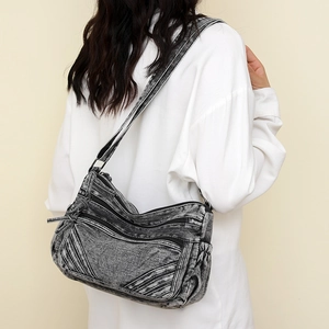 Detail of vintage black washed denim crossbody bag with multiple zipper pockets