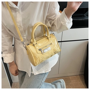 Primer plano de un bolso cilíndrico amarillo brillante con herrajes plateados