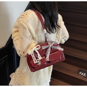 Detail of red patent leather shoulder bag with lace ribbons and heart pendants