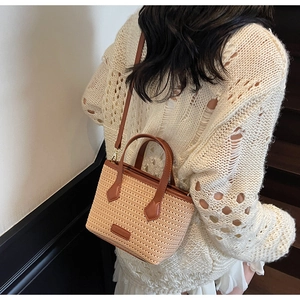 Model wearing a knit bucket bag with brown leather straps on a warm staircase background