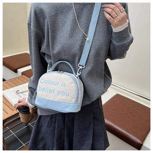Blue and beige canvas bowling bag with adjustable strap worn by a model in a cafe