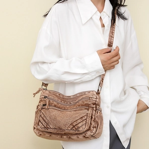 Detail of vintage brown denim crossbody bag featuring dual front zippers and side pockets