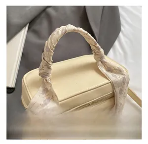 Detail of cream mini box bag featuring a top handle wrapped in taupe checkered silk scarf