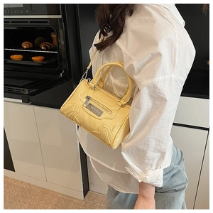 Detalle de bolso bandolera amarillo brillante con logo Lazy Breeze y hebillas de metal
