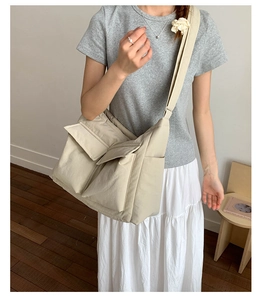 Detail of minimalist cream canvas crossbody bag with large front utility pockets and wide strap