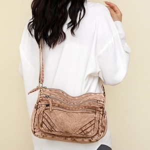 Detail of vintage washed canvas crossbody bag with multiple zipper pockets on model