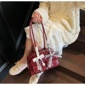 Detail of red patent leather shoulder bag with decorative lace bows and silver heart charm
