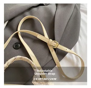 Macro shot of adjustable beige leather bag strap with a gold metal buckle detail