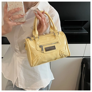 Detalle de un mini bolso boston amarillo brillante con logo metálico Lazy Breeze