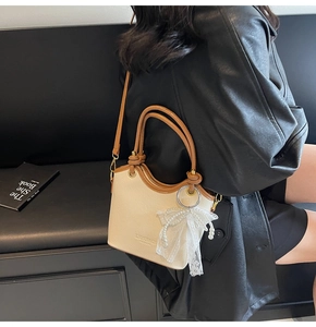 Détail du sac seau contrasté crème et marron avec nœud en perles et dentelle