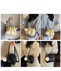 Detail of drawstring bucket bag in yellow and black PU leather with plush pompom