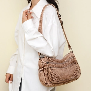 Detail view of washed tan crossbody bag featuring multi-pocket utility and wide strap