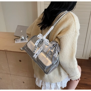 Silver metallic shoulder bag detail with lace bows and heart-shaped metal charms