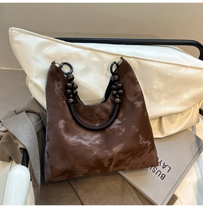 Detailed view of brown marble pattern tote bag with decorative beaded handle and U-knot