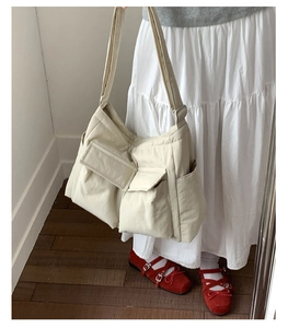 Detail of a large off-white canvas tote bag with functional flap pockets and side pocket