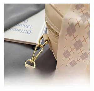 Detail of beige bucket bag featuring gold hardware hooks and a decorative silk scarf