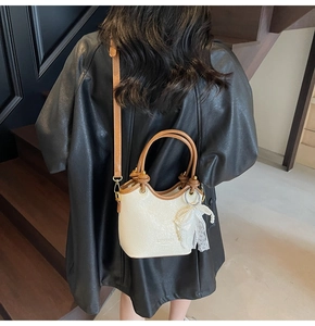 Détail du sac seau crème avec nœud en dentelle et perles et poignée en cuir brun