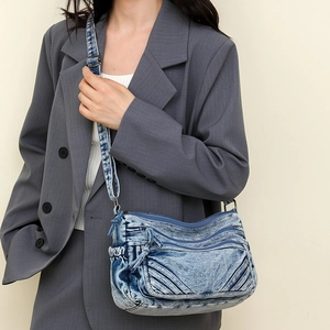 Detail of vintage washed denim crossbody bag with dual front zippers and textured finish