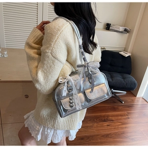 Close-up of silver shoulder bag featuring lace bows, ribbon, and heart pendant detail