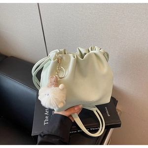 Detail of mint green drawstring bucket bag with cute plush sheep pendant on books