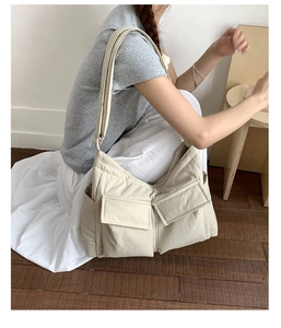 Detail of a large beige quilted canvas messenger bag with functional front flap pockets