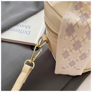 Détail du sac à main crème montrant le fermoir doré et le foulard en soie à motifs violets