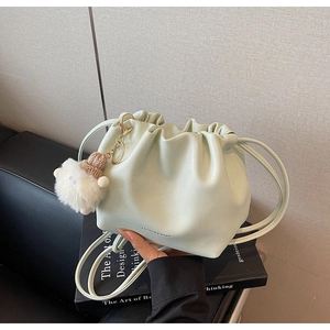 Close-up of mint green pleated drawstring bucket bag with a cute plush doll charm