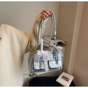 Detail of silver metallic handbag featuring lace bows and heart pendants with dual straps