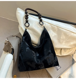 Detail of black tote bag featuring unique dark-toned wooden bead handles and textured fabric