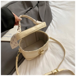 Détail du sac boîte beige crème avec poignée en foulard de soie et accents dorés clairs