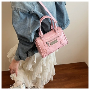 Detalle de bolso Boston rosa brillante con logo metálico Lazy breeze y costuras onduladas