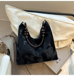 Detail of black hobo bag featuring a unique dark brown round wooden bead shoulder strap