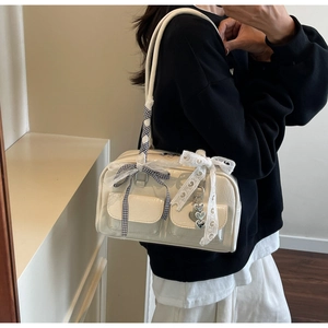 Detail of cream patent leather bag featuring lace bows and heart-shaped metal charms