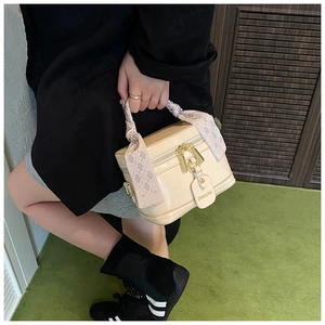 Détail d'un sac à main boîte beige avec poignée en soie et étiquette de marque