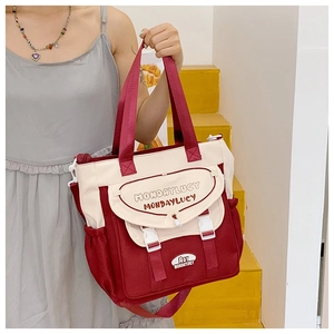 Close-up of red and white canvas crossbody bag featuring a buckled flap and carry handle