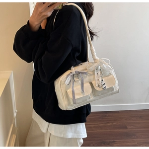Close-up of cream shoulder bag featuring lace bows, plaid ribbon and heart charms