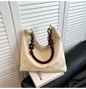 Detail of cream tote bag featuring wooden bead handles and woven rope accents