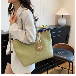 Détail du sac cabas vert clair avec texture litchi et breloque fleur de perle au quotidien