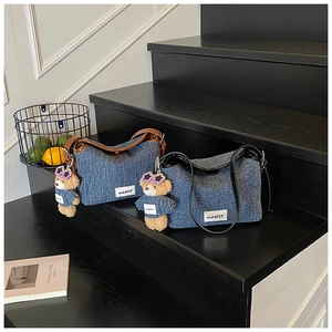 Detail of denim bucket bags with leather trim and cute teddy bear charms on stairs