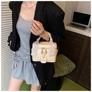 Détail d'un sac à main boîte beige avec poignée en foulard de soie et fermeture dorée