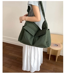 Close-up of olive green canvas messenger bag with large front pockets and wide strap
